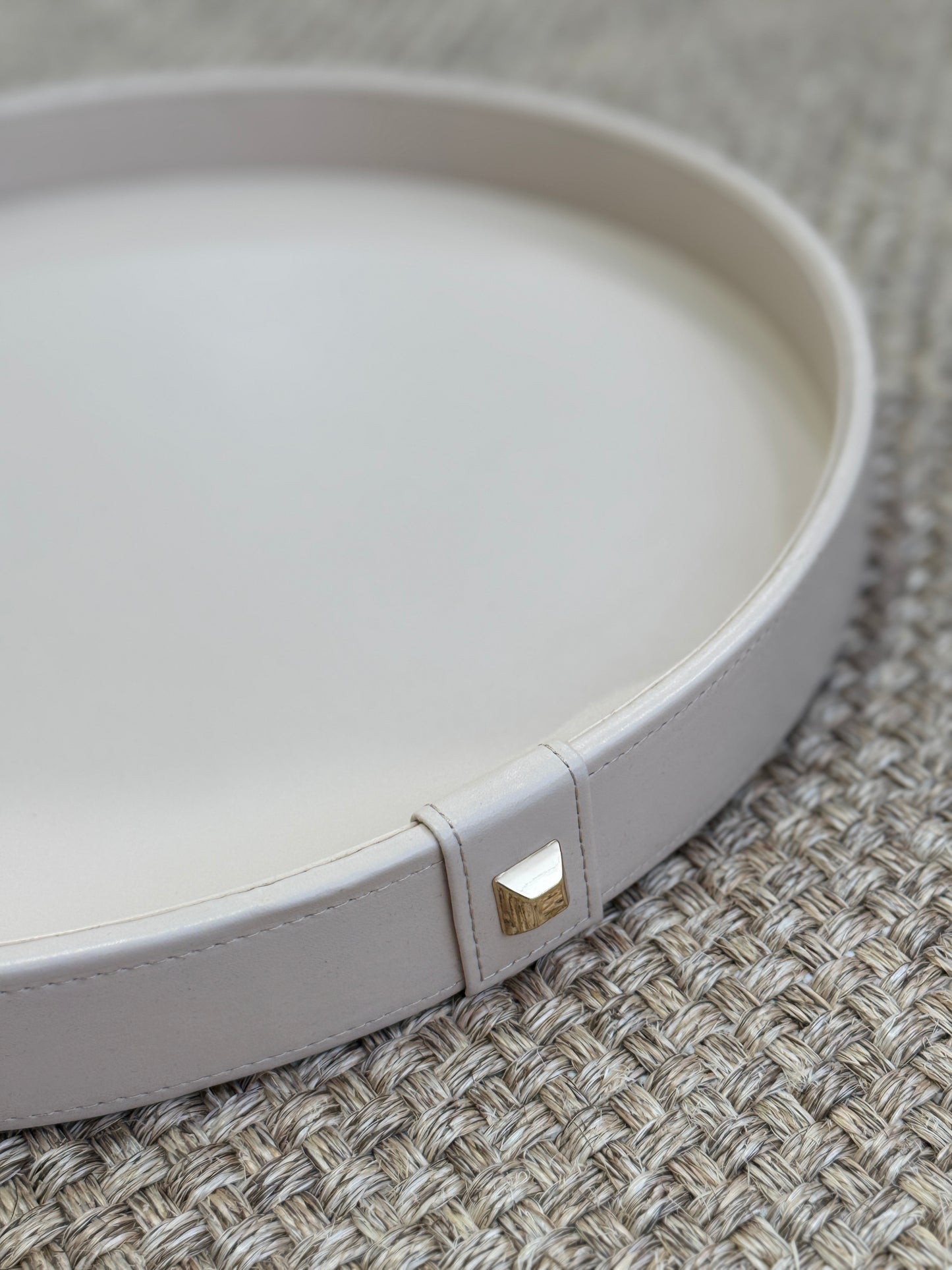 Vista superior de bandeja decorativa redonda en polipiel beige con botón dorado, diseño elegante y minimalista