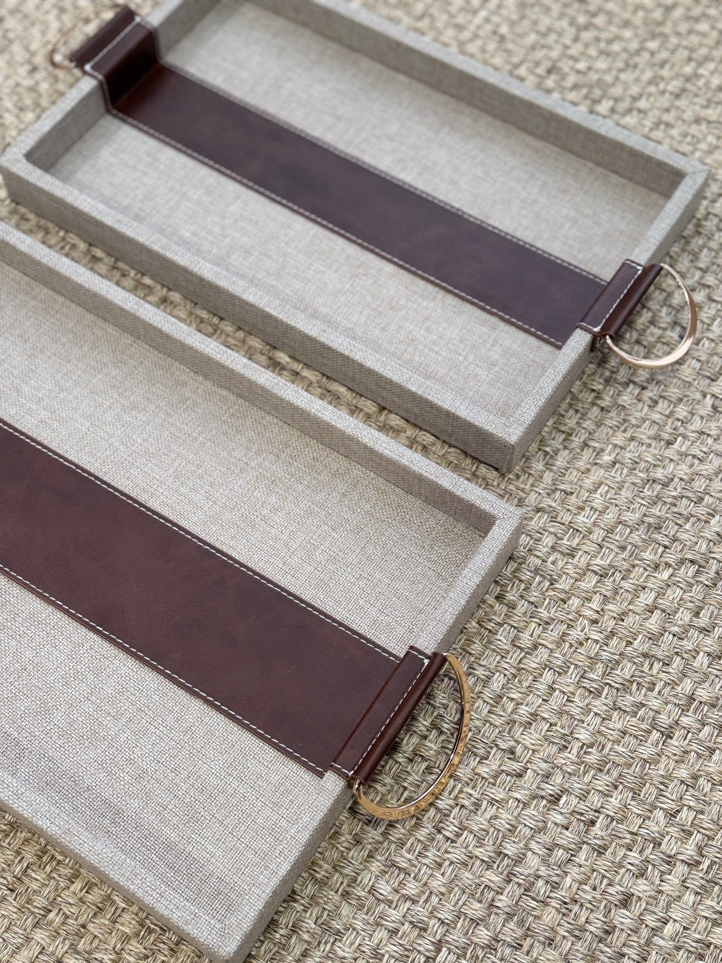 Detalle de bandeja decorativa rectangular con polipiel marrón y asas doradas