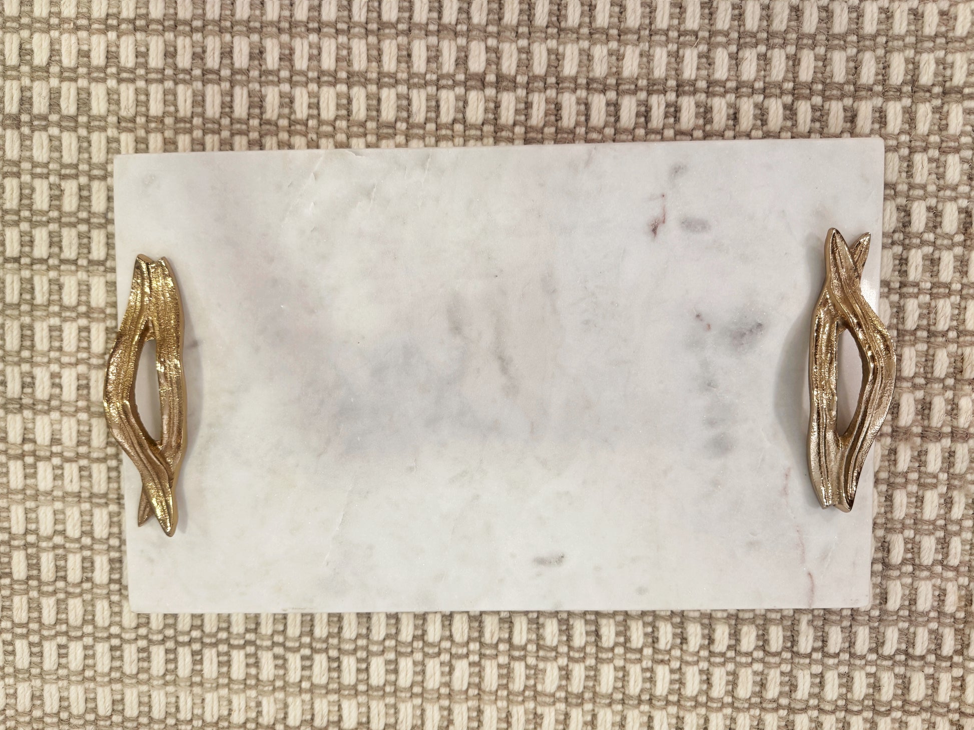 Detalle de bandeja rectangular en mármol natural con asas doradas