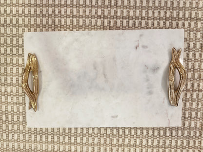 Detalle de bandeja rectangular en mármol natural con asas doradas