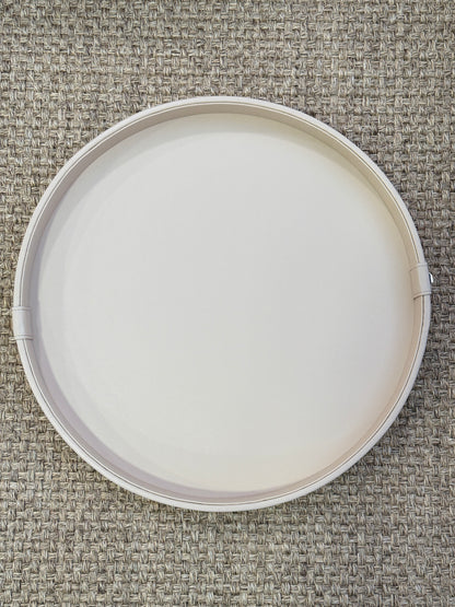 Detalle de bandeja redonda en polipiel beige con botón dorado, base de madera para mesa de centro