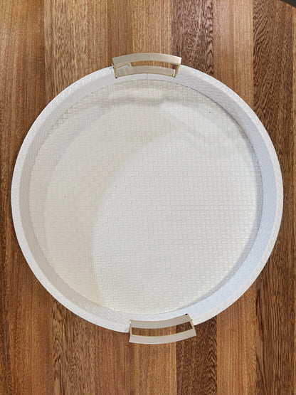 Vista superior de bandeja redonda en polipiel blanca con asas doradas de acero inoxidable, acabado premium