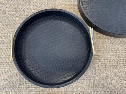 Vista superior de bandeja redonda en polipiel negra con asas doradas de acero inoxidable, acabado premium