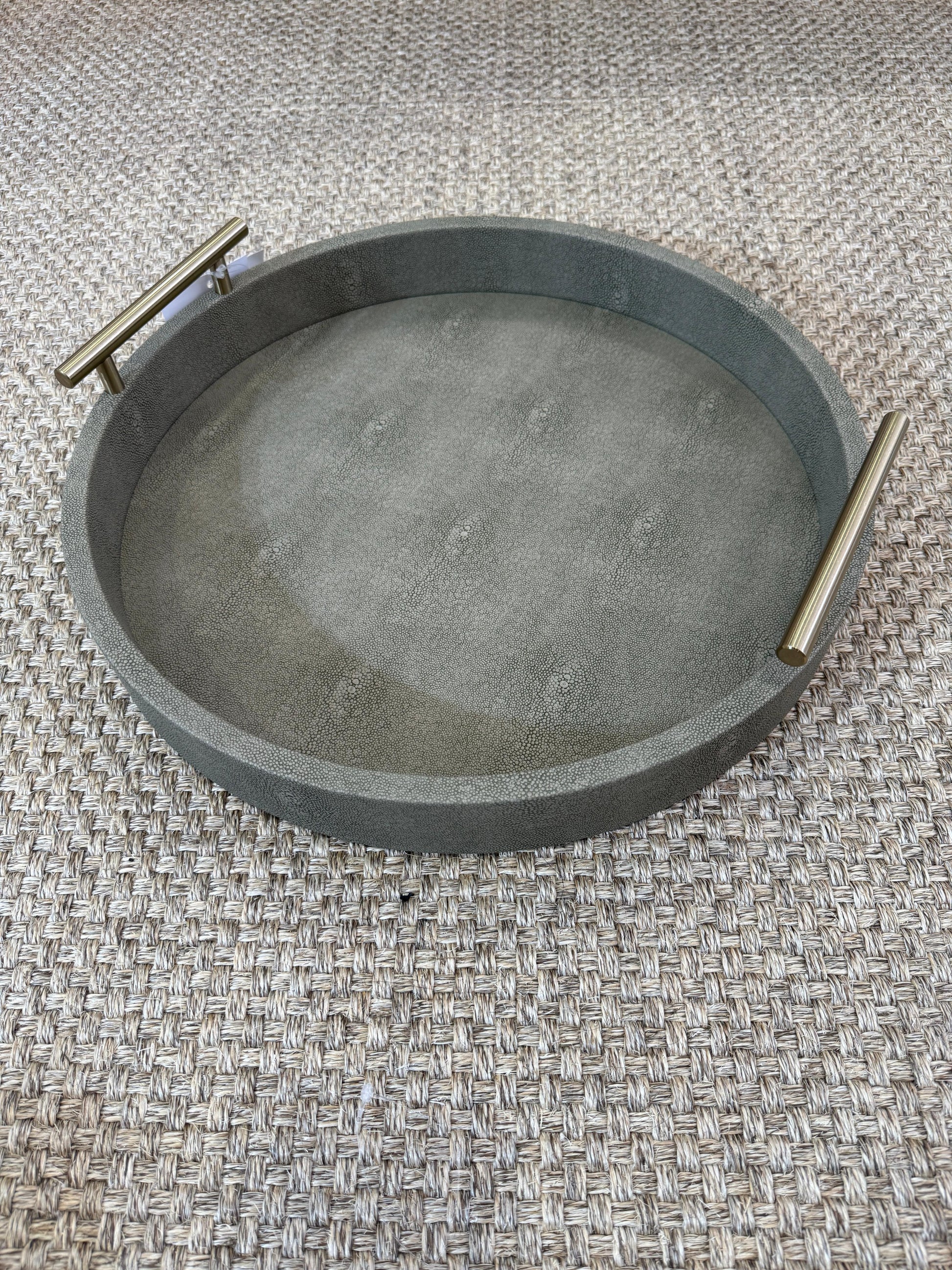 Vista superior de bandeja redonda en polipiel verde olivo con asas doradas de acero inoxidable, acabado premium