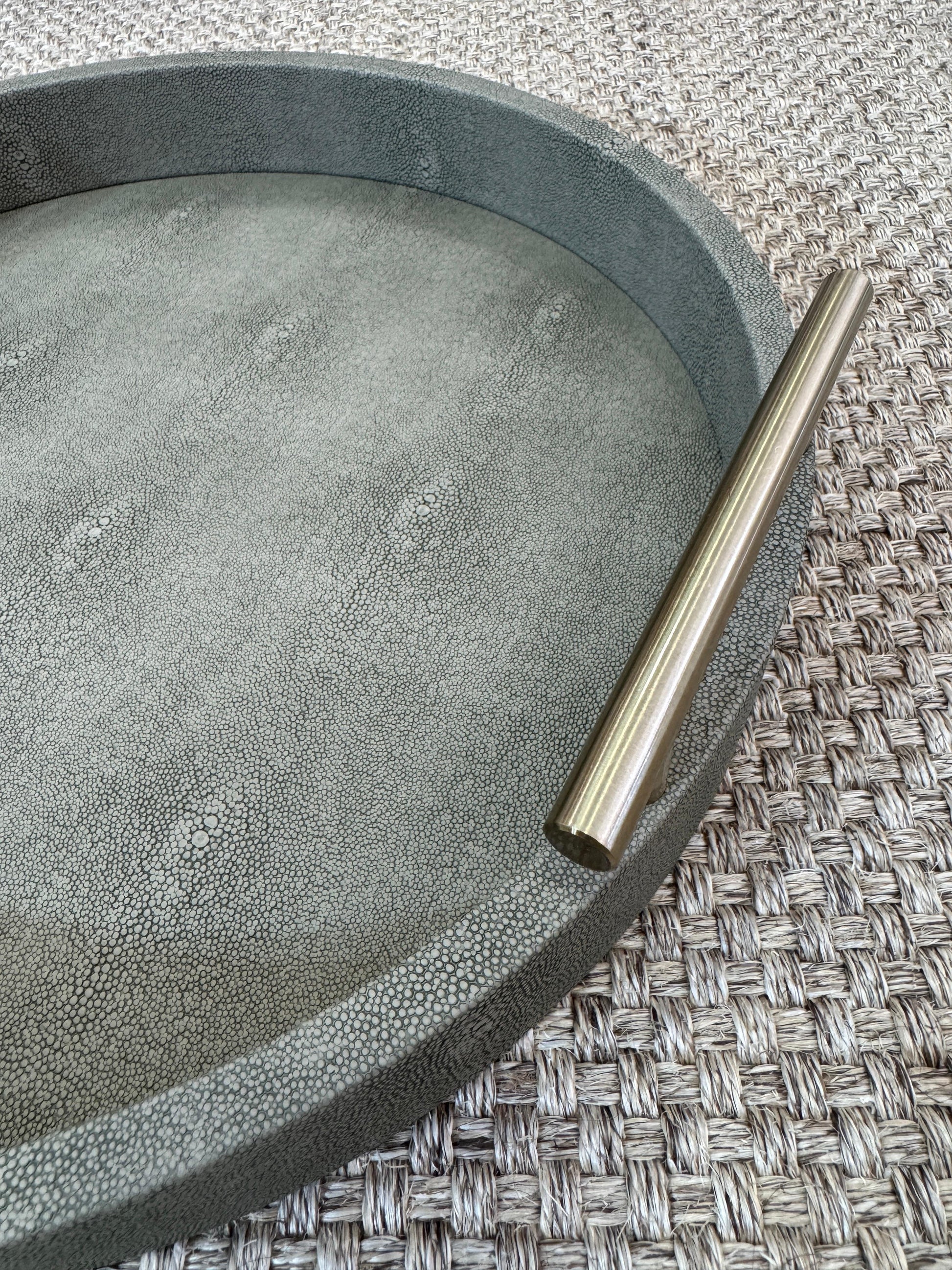 Detalle de bandeja redonda verde olivo con asas doradas, base de madera revestida en polipiel para decoración