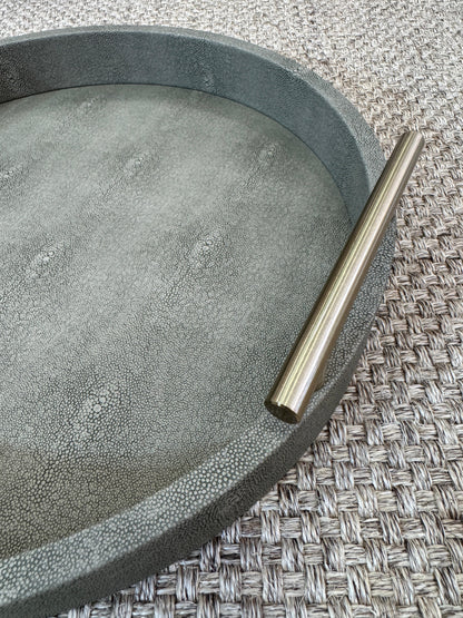 Detalle de bandeja redonda verde olivo con asas doradas, base de madera revestida en polipiel para decoración