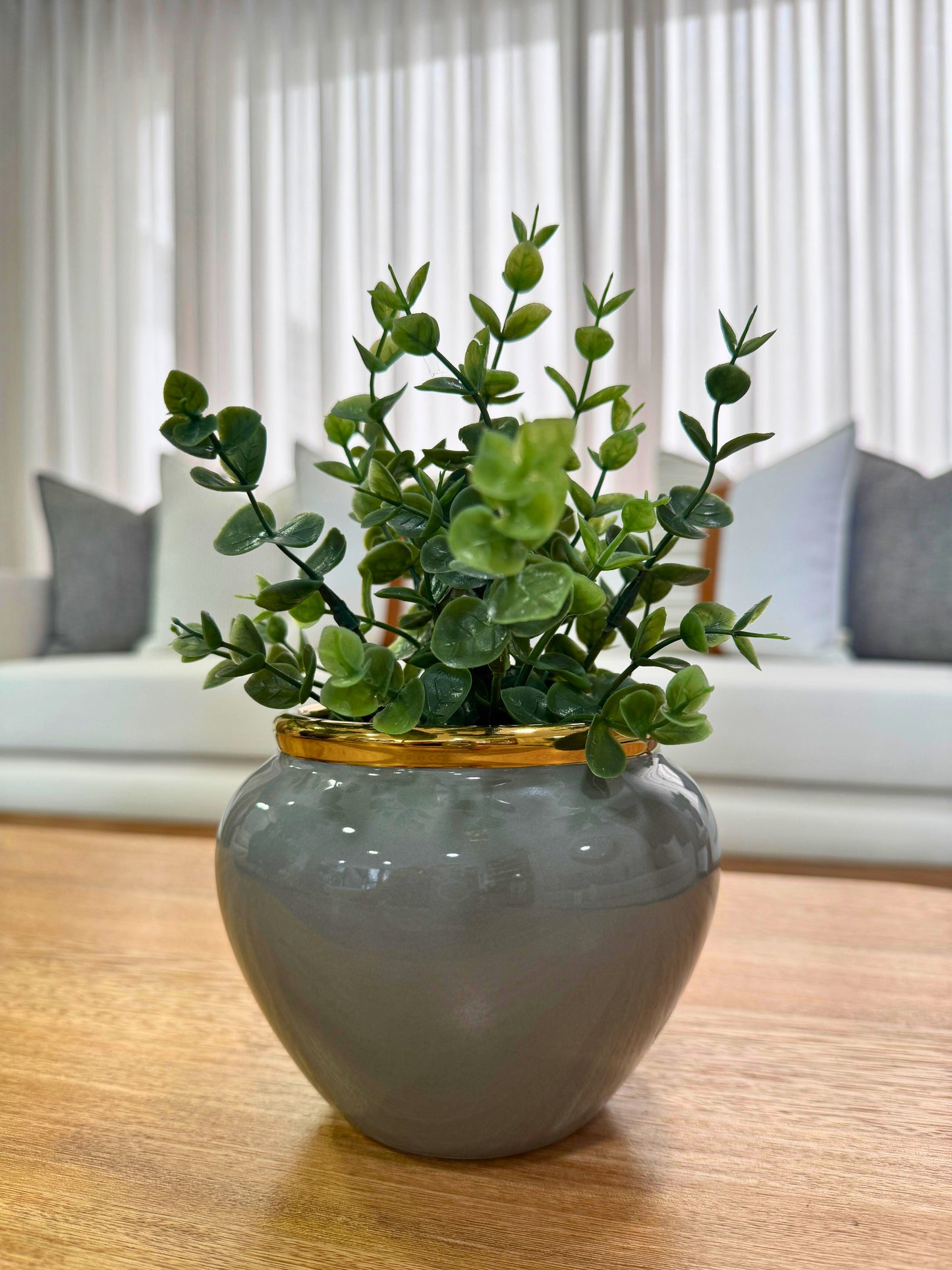 Detalle de jarrón de cerámica gris con borde dorado, florero decorativo con acabado brillante