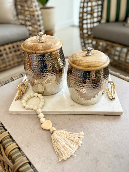 Detalle de borlas decorativas blancas con corazón de madera natural
Detalle de ánforas decorativas en aluminio con tapa de madera, jarrones modernos para decoración