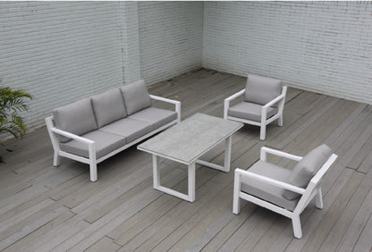 Detalle de sala SALINE blanca, sofás de aluminio con cojines taupe y mesa altura comedor
