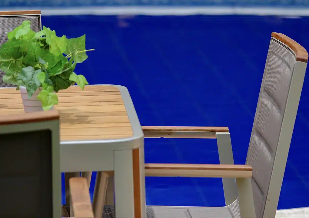 Detalle de comedor CEDAR gris, sillas apilables de aluminio con textilene y madera teca
