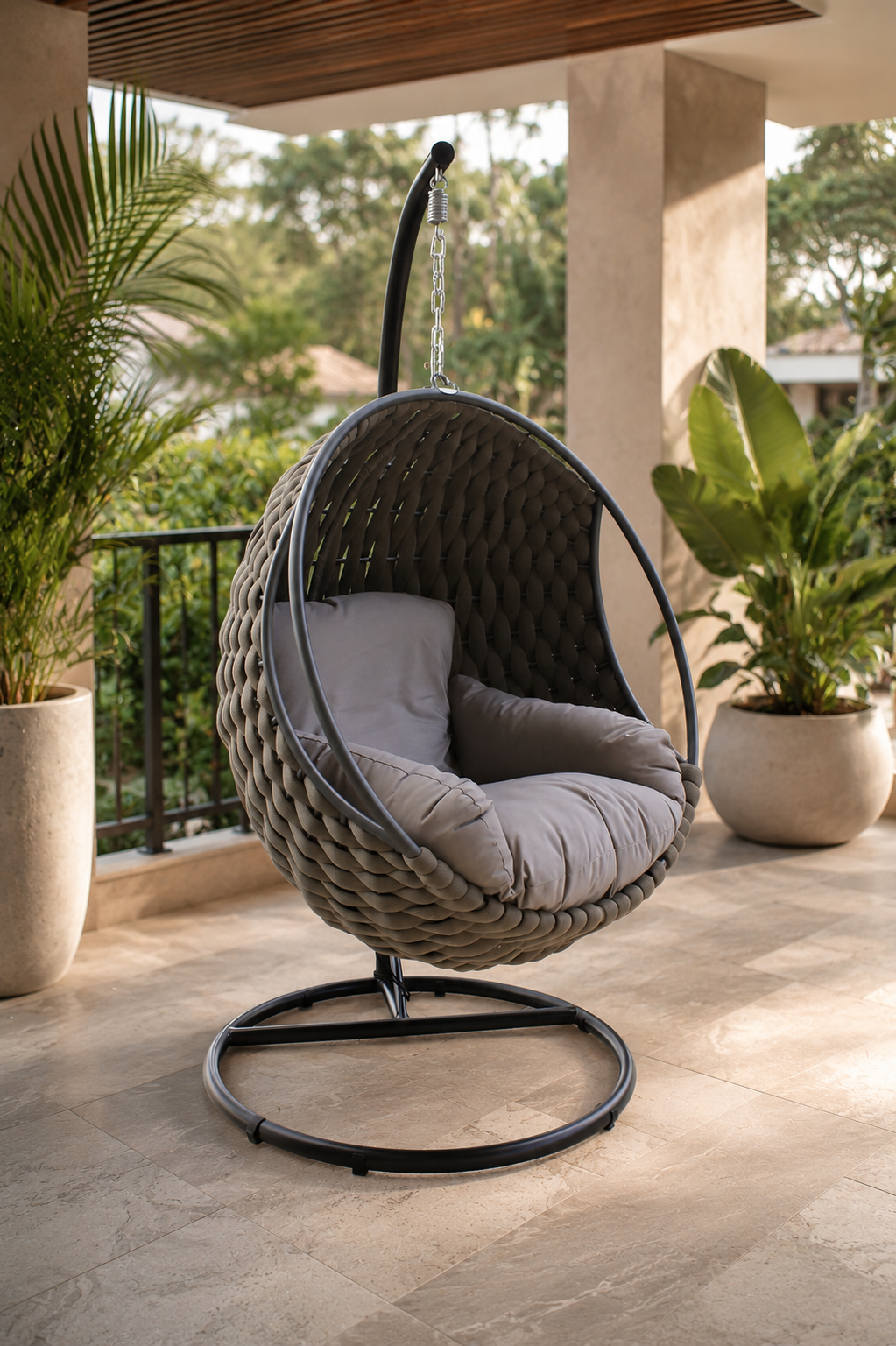 Silla colgante ROPE taupe para terraza cubierta, con base circular metálica negra y cojinería acolchada.